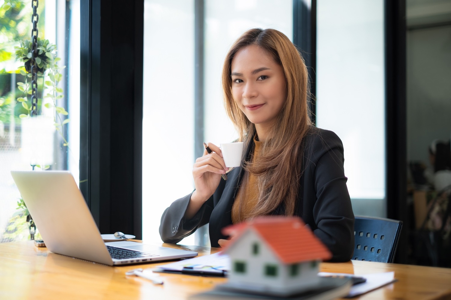asesora inmobiliaria mira a camara sonriente con cafe en mano