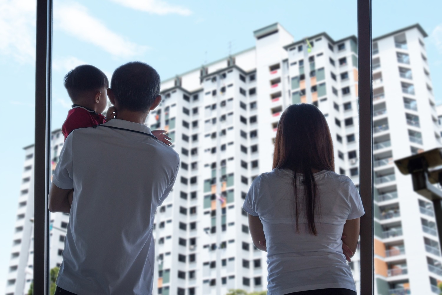 pareja con hijo de espaldas mrando edificio desde ventana